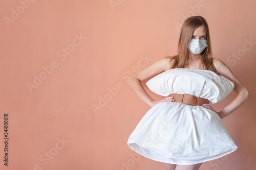 Beautiful girl in a pillow dress smiles with copy space. Crazy quarantine concept photo