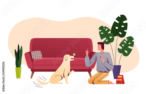 Young man is training a dog in the living room. Man spends time with his pet at home. People and home daily activities