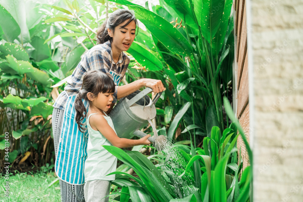 Obraz premium happy mother and daugther watering her garden together at home