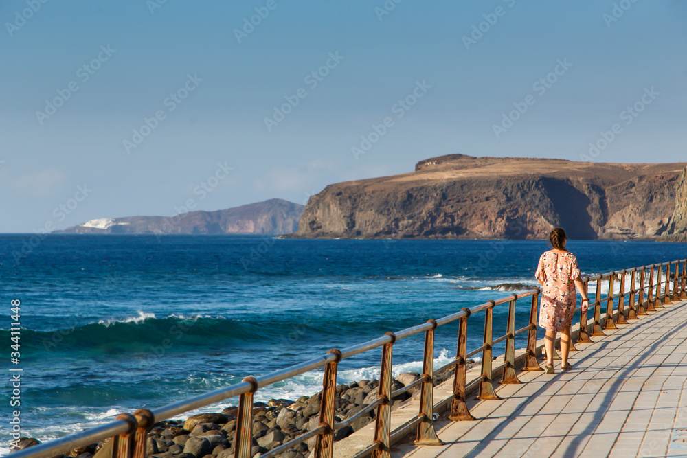 Young woman walks alongside the Atlantic Ocean, the coast of Gran Canaria