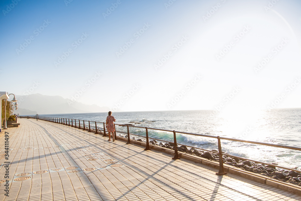 Young woman walks alongside the Atlantic Ocean, the coast of Gran Canaria