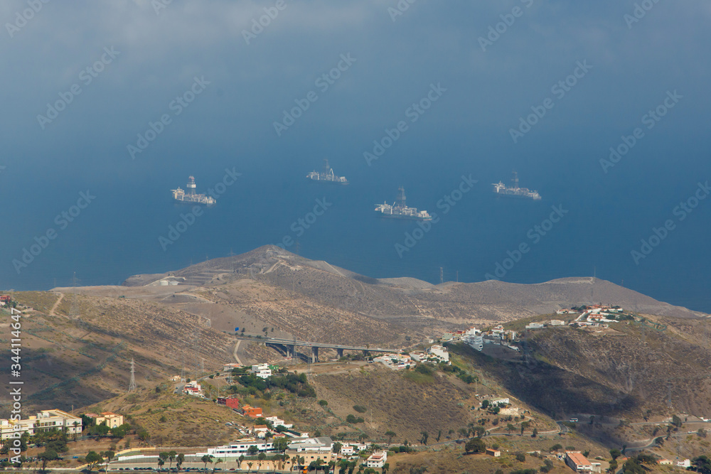 Fototapeta premium Top view of Gran Canaria mountains and sea on cloudy day. Nature landscape with small towns on valley and ships on background