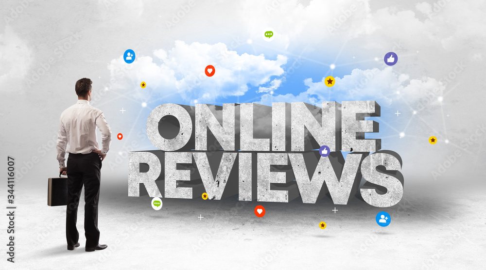 Young businessman standing in front of ONLINE REVIEWS inscription, social media concept Young businessman standing in front of ONLINE REVIEWS inscription, social media concept