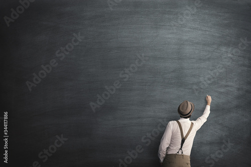 student writing on an empty blackboard with chalk photo