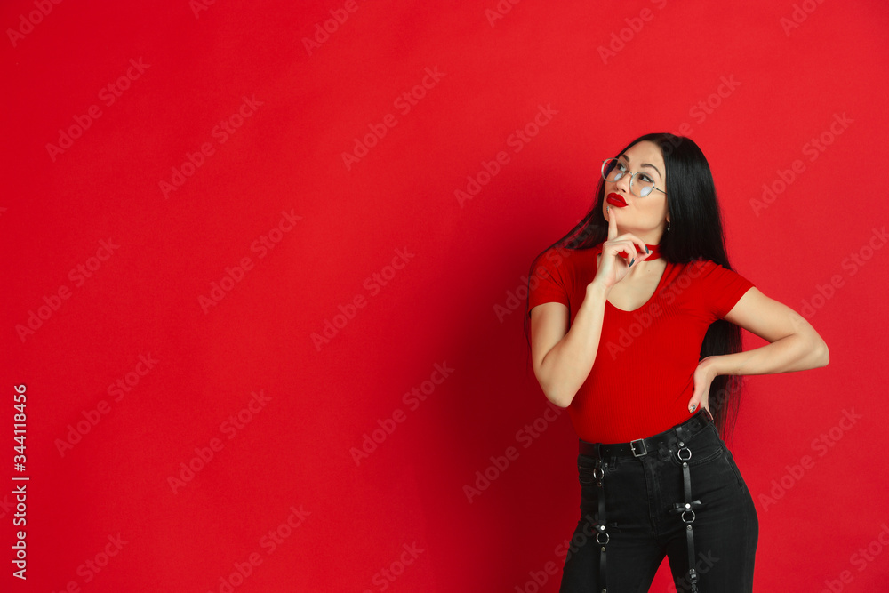 Thoughful, thinking. Caucasian young woman's monochrome portrait isolated on red studio background. Beautiful female brunette model. Concept of human emotions, facial expression, sales, ad. Thoughful, thinking. Caucasian young woman's monochrome portrait isolated on red studio background. Beautiful female brunette model. Concept of human emotions, facial expression, sales, ad.