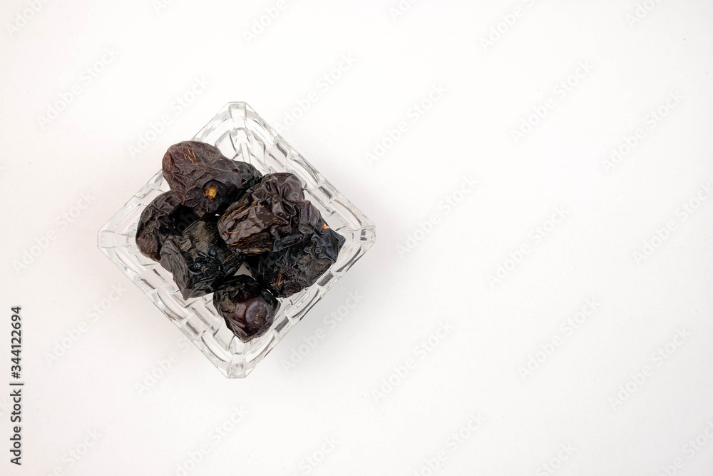 Top view of dates on glassware over white. High in natural sugar packed with plenty of nutrients. Conceptual of breaking fast in ramadhan. Top view of dates on glassware over white. High in natural sugar packed with plenty of nutrients. Conceptual of breaking fast in ramadhan.