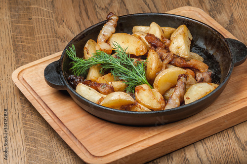 fried potatoes in a pan with slices of bacon