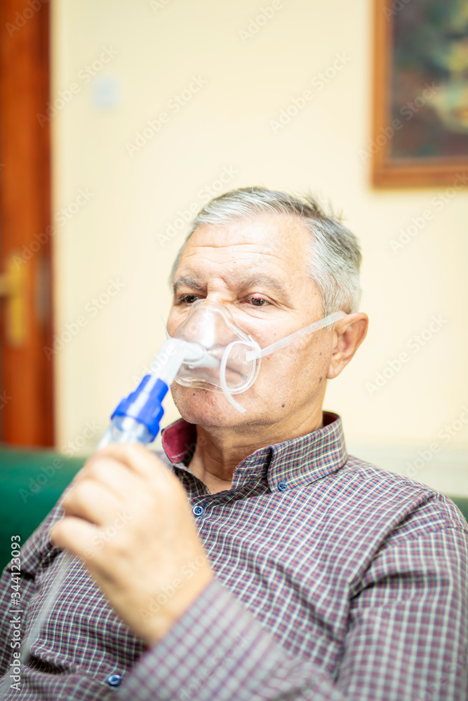Senior man using medical equipment for inhalation with respiratory mask, nebulizer Senior man using medical equipment for inhalation with respiratory mask, nebulizer