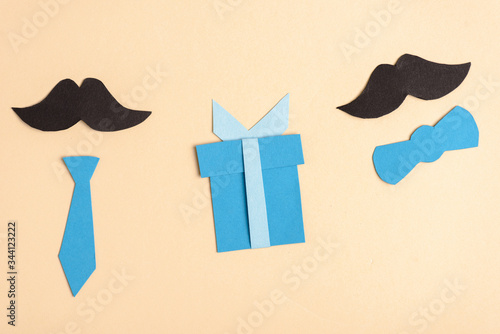 Top view of paper crafted fake mustache and decorative elements on beige background, fathers day concept
