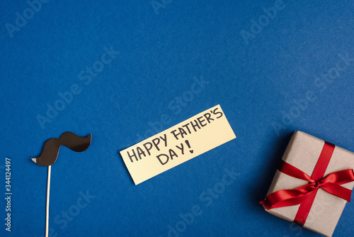 top view of paper decorative fake mustache from cardboard, gift box and greeting card with lettering happy fathers day photo