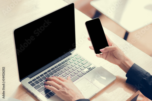 A woman uses a laptop at home while sitting at a wooden desk. Man hands typing on a notebook keyboard. Work from Home concept