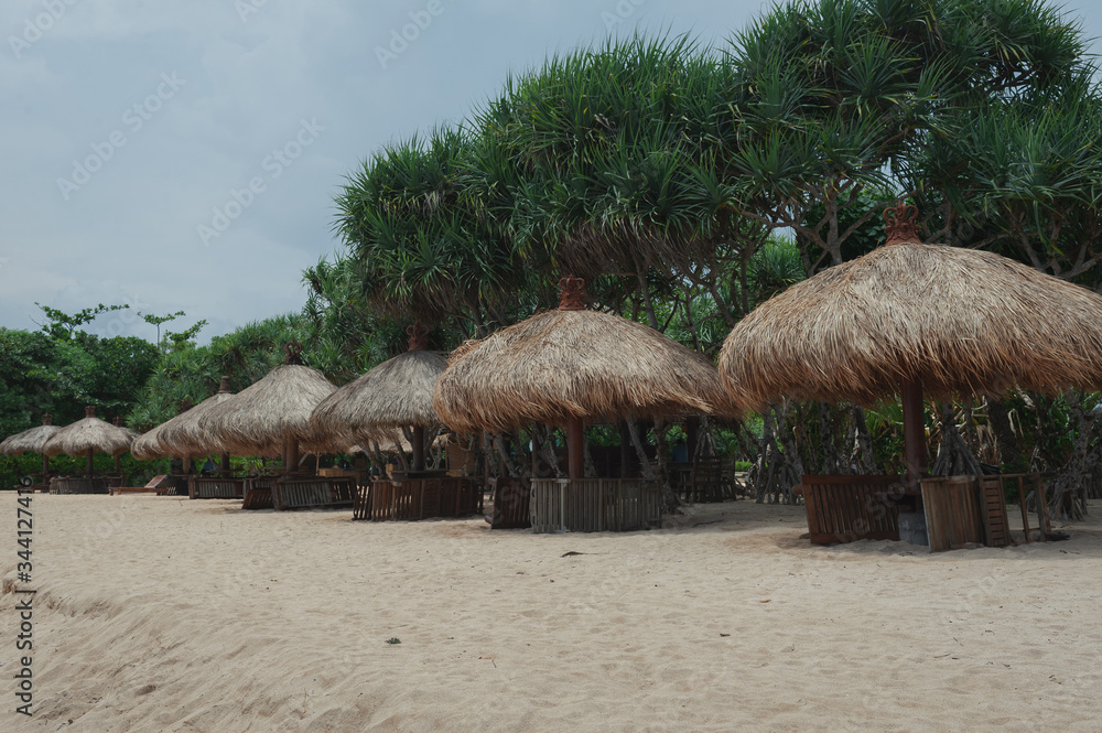 Beach umbrellas from straw on tropical sandy beach.