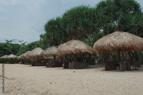 Beach umbrellas from straw on tropical sandy beach.