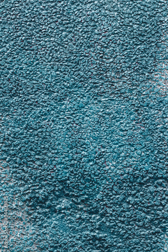 Background texture wall of a house covered with small pebbles fastened with mortar. Painted in blue. Vertical.
