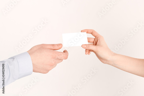 The girl s hand passes the credit card to the man s hand. Purchase of a plastic card with an online service close-up.