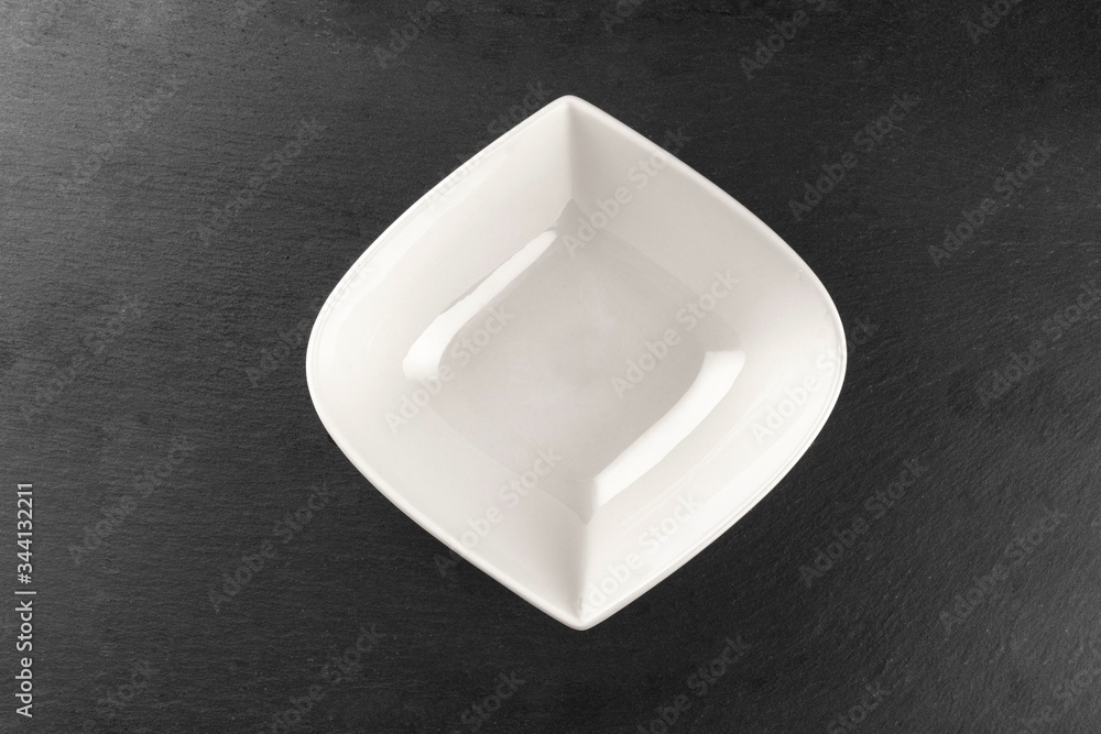 White plate on stone. Empty round dish isolated on dark. Food dinner background. Restaurant kitchen minimalistic concept. White plate on stone. Empty round dish isolated on dark. Food dinner background. Restaurant kitchen minimalistic concept.
