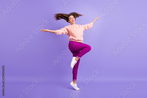Full body profile photo of funny lady jumping high up rejoicing spend lovely time throwing long hair up wear casual fur soft sweater pants sneakers isolated purple color background