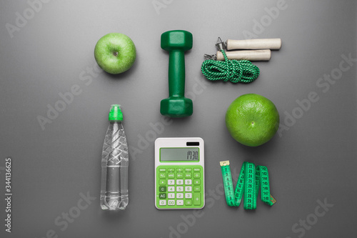 Attributes of a healthy lifestyle. Fruit, green dumbbell, water bottle, ruler, rope, on a neutral background. Counting calories. The diet plan. View from above. Close-up. Minimalism.