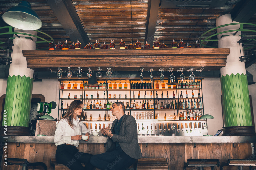 Cheerful caucasian man and woman talking, enjoying at the coffee shop, cafe, bar. Couple or friends, business partners drinking toghether, having a date, romantic. Communication, relations concept.