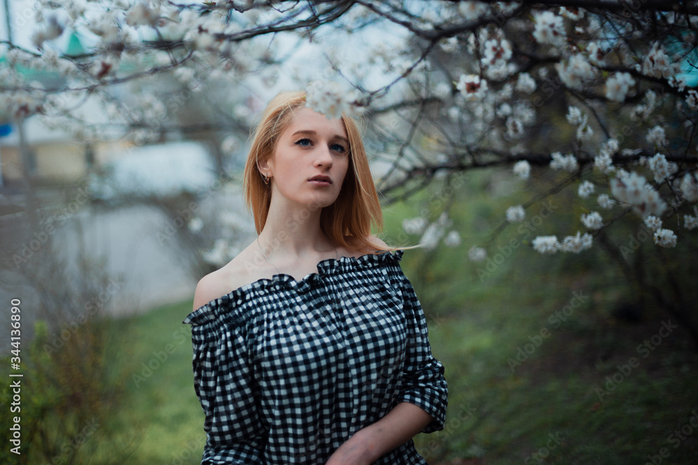 Beautiful young blonde girl on a background of flowering trees Beautiful young blonde girl on a background of flowering trees