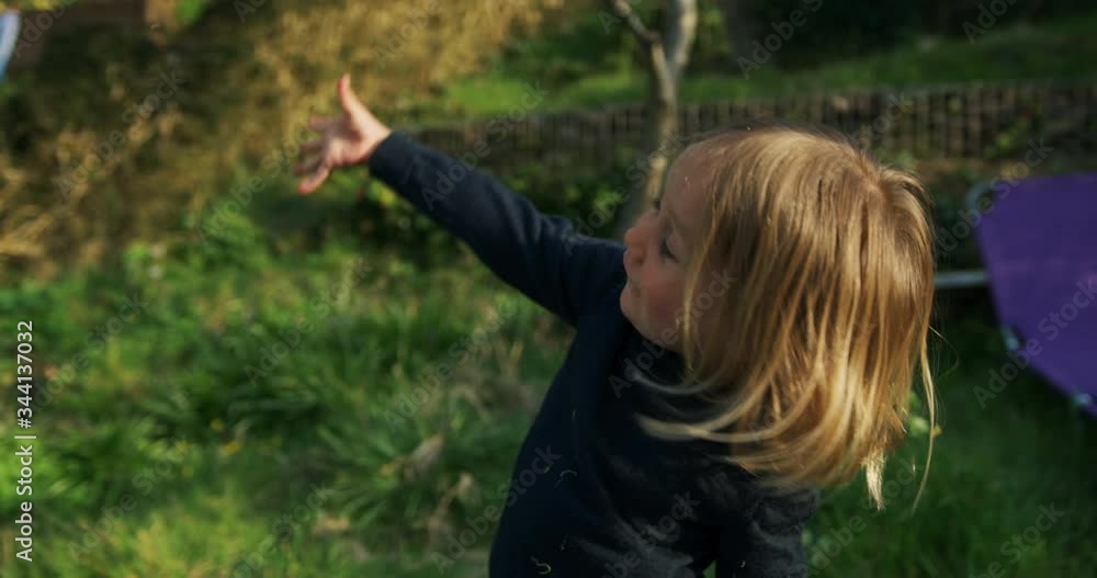 Preschooler boy in the garden throwing cut grass in the air at sunset Preschooler boy in the garden throwing cut grass in the air at sunset