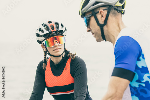 Male and female cyclists near sea. Athletic man and woman in sportswear riding bicycles and talking on sea coast. Triathlon Concept