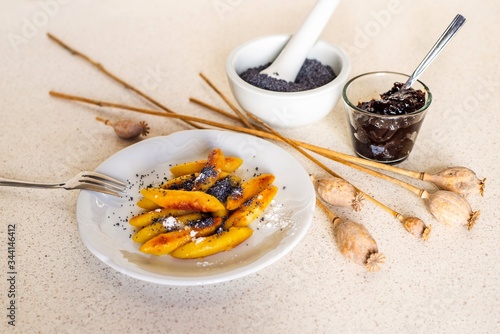 Sweet potato dumplings (wedges) with poppy seeds, poppy heads, plum jam, mortar. photo