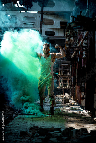 a man with a sports figure in the factory confidently passes through green smoke.