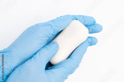 Female hands in rubber gloves hold a bar of soaps