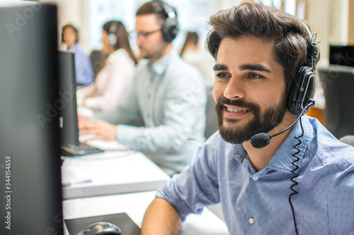 Close-up portrait of smiling assistant using a headset in a call center