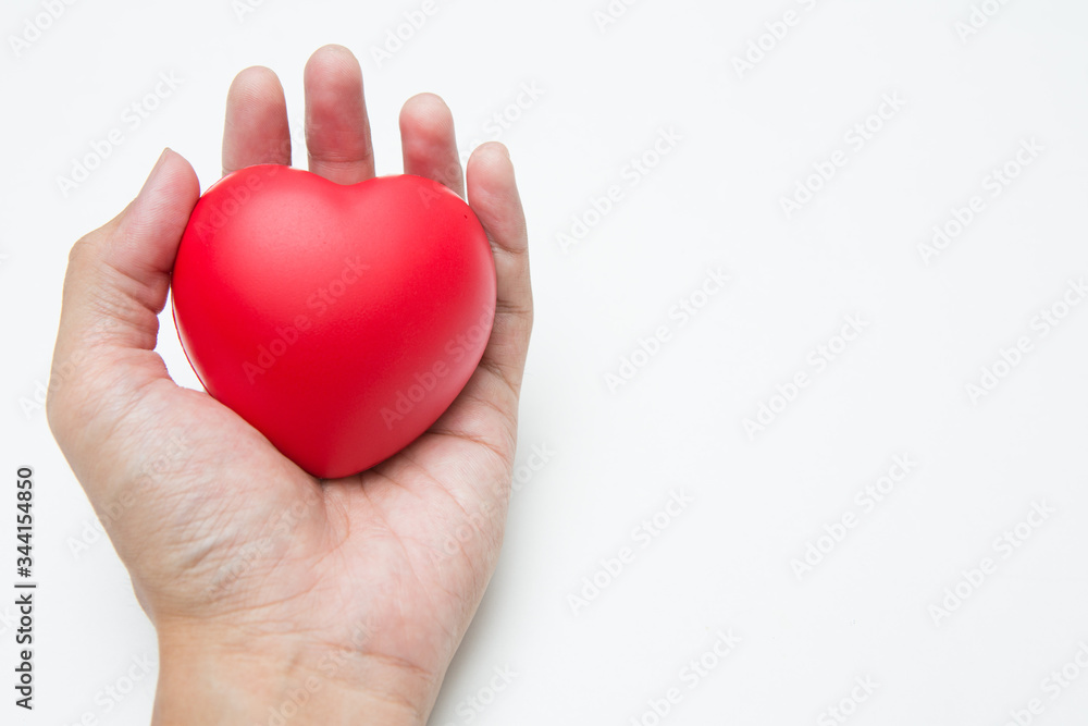 Obraz premium The hand is holding Heart shaped squeeze ball for hand muscle exercise on white background and copy space