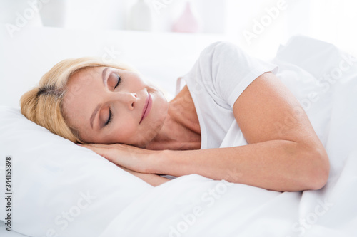 Close-up portrait of her she nice attractive lovely cute pretty calm aged woman lying in bed sleeping enjoying silence in modern light white interior room flat apartment indoors