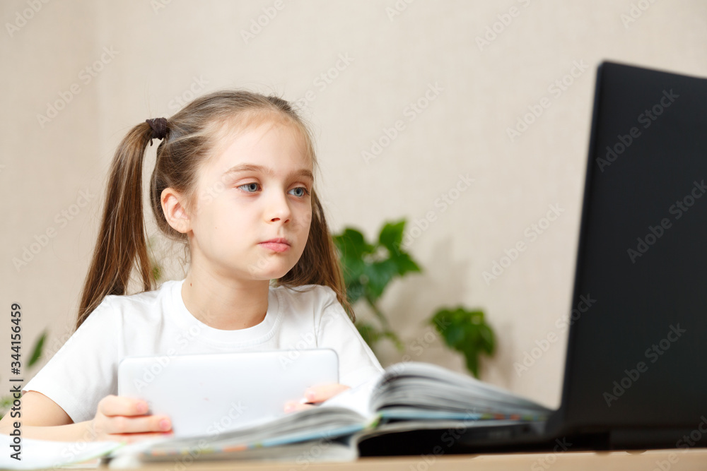 Little girl doing her homework at home and using a laptop Little girl doing her homework at home and using a laptop