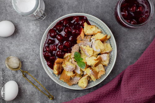 Kaiserschmarren or Kaiserschmarrn is a traditional Austrian or German sweet pancake dessert, with icing sugar and berry, cherry sauce or rote grutze jam. Top view.  photo