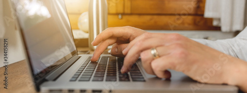 Close-up unrecognizable man hands typing in keyboard laptop. On a wooden desk.