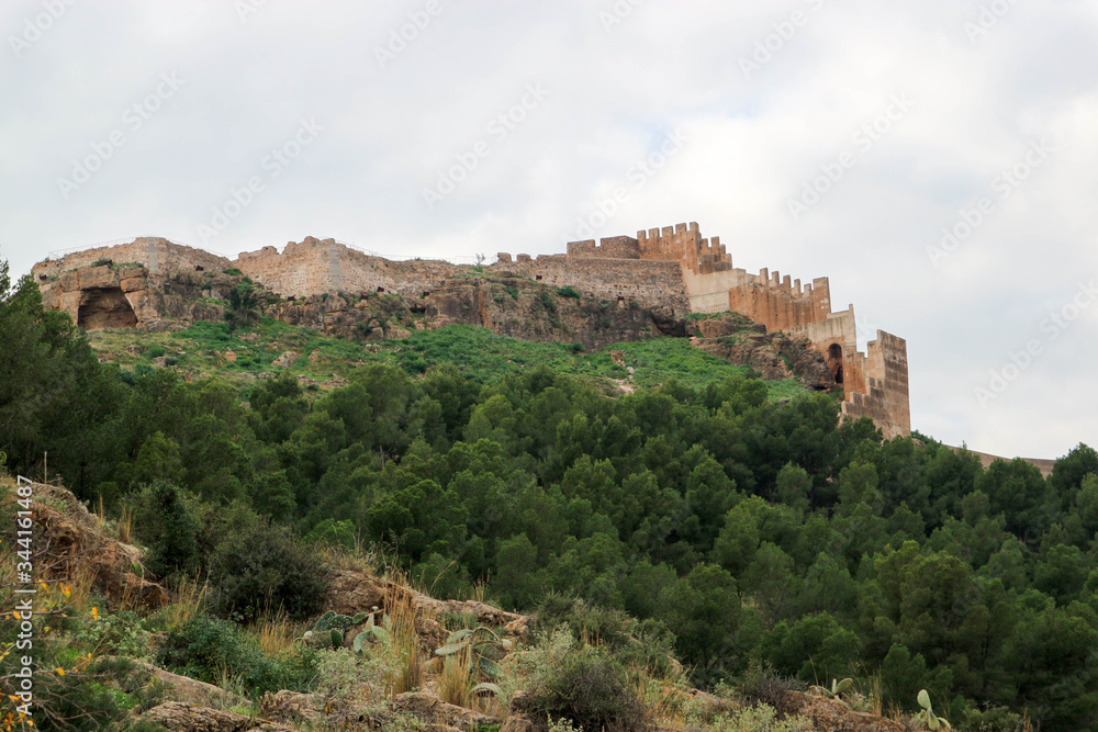 Walls and towers of old medieval Sagunto impregnable fortress ruin on a hill in Spain surrounded by green forest