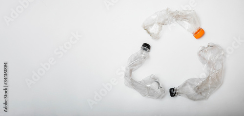 Three plastic water bottles bent and put together to make up recycle symbol. Objects isolated on white background with copy space for text.