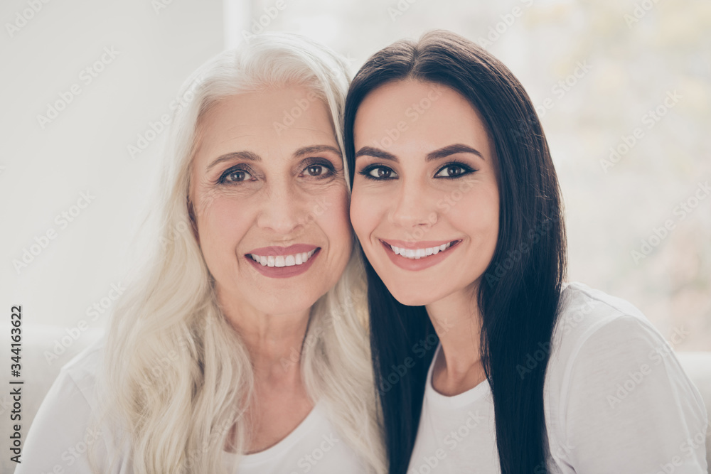 Close-up portrait of two nice attractive lovely tender cheerful women mom mommy adult daughter spending time day together in white light interior house flat apartment indoors Close-up portrait of two nice attractive lovely tender cheerful women mom mommy adult daughter spending time day together in white light interior house flat apartment indoors
