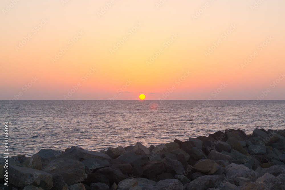 Sunset over the sea, stones in the foreground