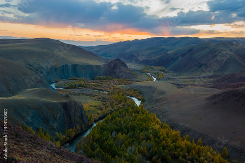 Sunset, winding river against the background of mountains and autumn trees, Altai