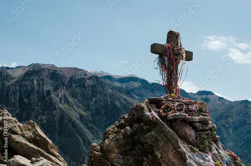 Cruz de piedra adornada con cintas de colores en las montañas de Peru