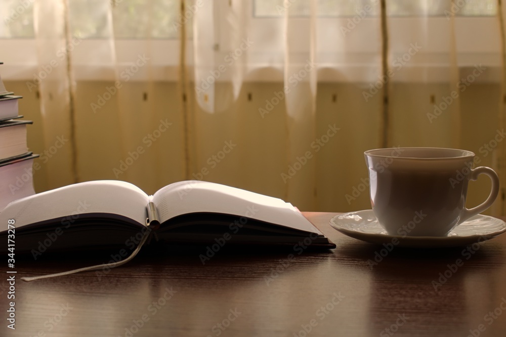 a diary and a cup of tea on the table on a sunny morning a diary and a cup of tea on the table on a sunny morning