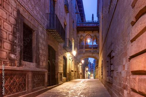 Narrow cobbled medieval Carrer del Bisbe street with Bridge of Sighs in Barri Gothic Quarter in the morning  Barcelona  Catalonia  Spain