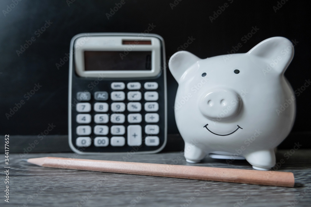 piggy bank with distinctive pencil and a calculator showing savings and discipline piggy bank with distinctive pencil and a calculator showing savings and discipline