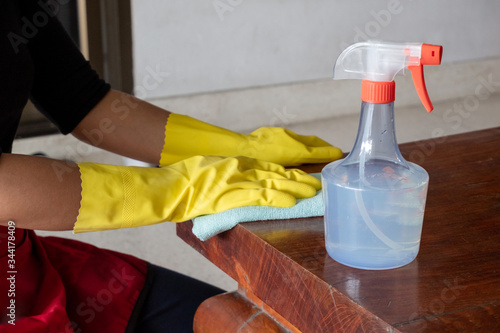 Obraz na płótnie The happy housewives in rubber gloves wipe the dust with a spray while cleaning
