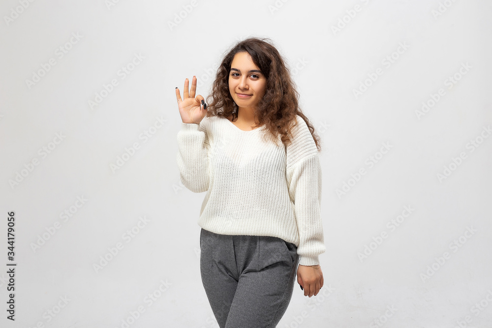 Portrait of happy smiling young woman showing okay gesture, isolated over white background. Beautiful young woman portrait. Indoor portrait of beautiful brunette young woman with shaggy hairstyle. Portrait of happy smiling young woman showing okay gesture, isolated over white background. Beautiful young woman portrait. Indoor portrait of beautiful brunette young woman with shaggy hairstyle.
