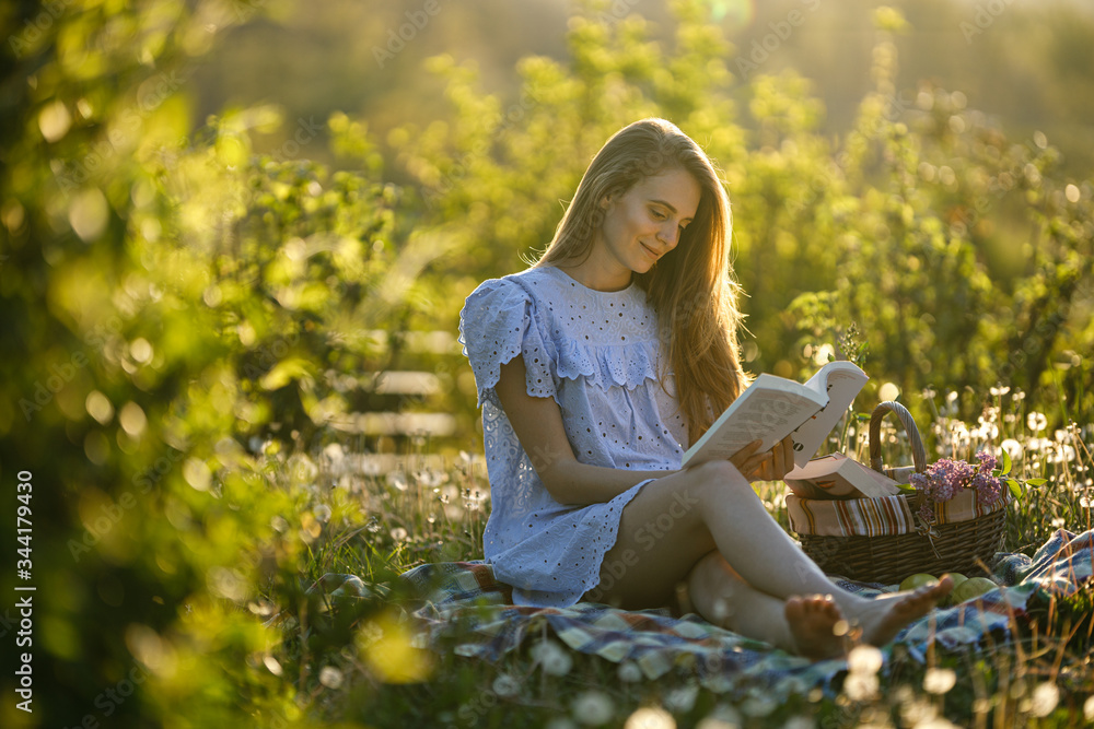young woman in the park with dandelions reading a book young woman in the park with dandelions reading a book