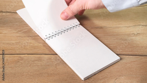 Hand turns over the notepad sheets for your text. Close up.