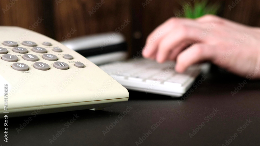 Hands of a man is using a computer, typing on keyboard, call the phone. Hands of a man is using a computer, typing on keyboard, call the phone.