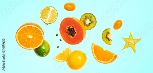 Flying fruits healthy summer background. Papaya, orange, kiwi, melon. Levitation, falling fly fruit on blue. Tropical creative concept. Colorful fruity summertime vivid design